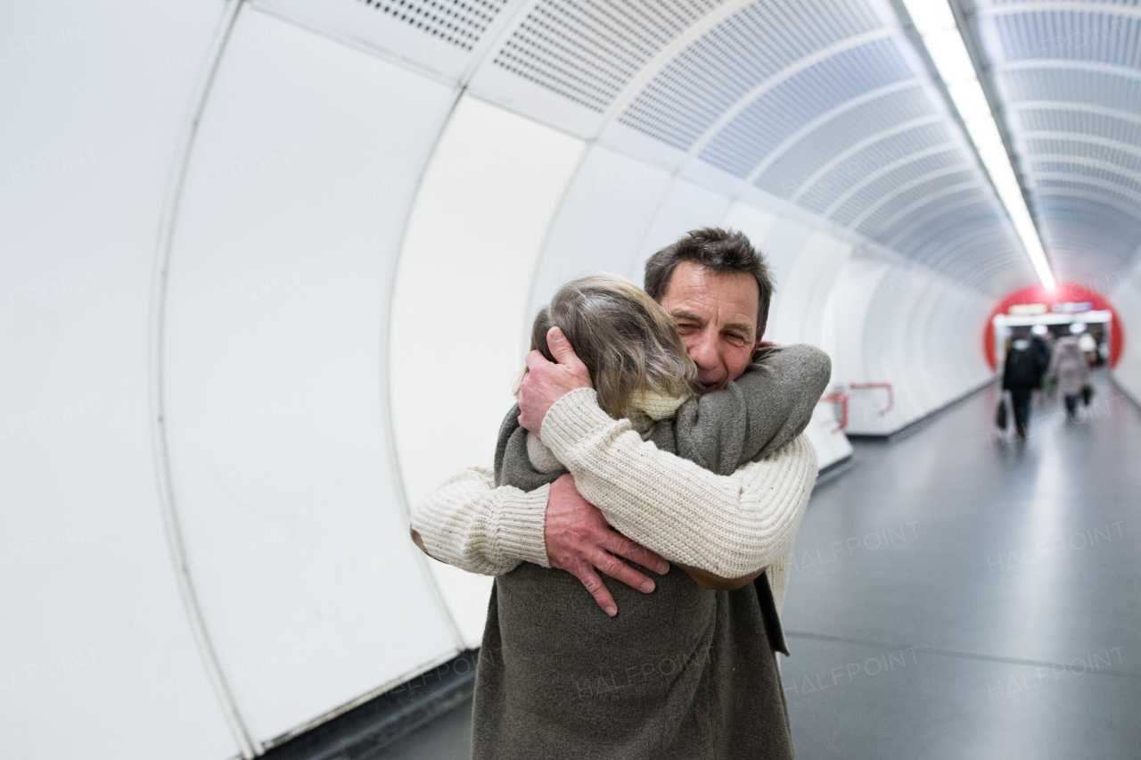 Beautiful senior couple in winter clothes in the hallway of subway in Vienna hugging