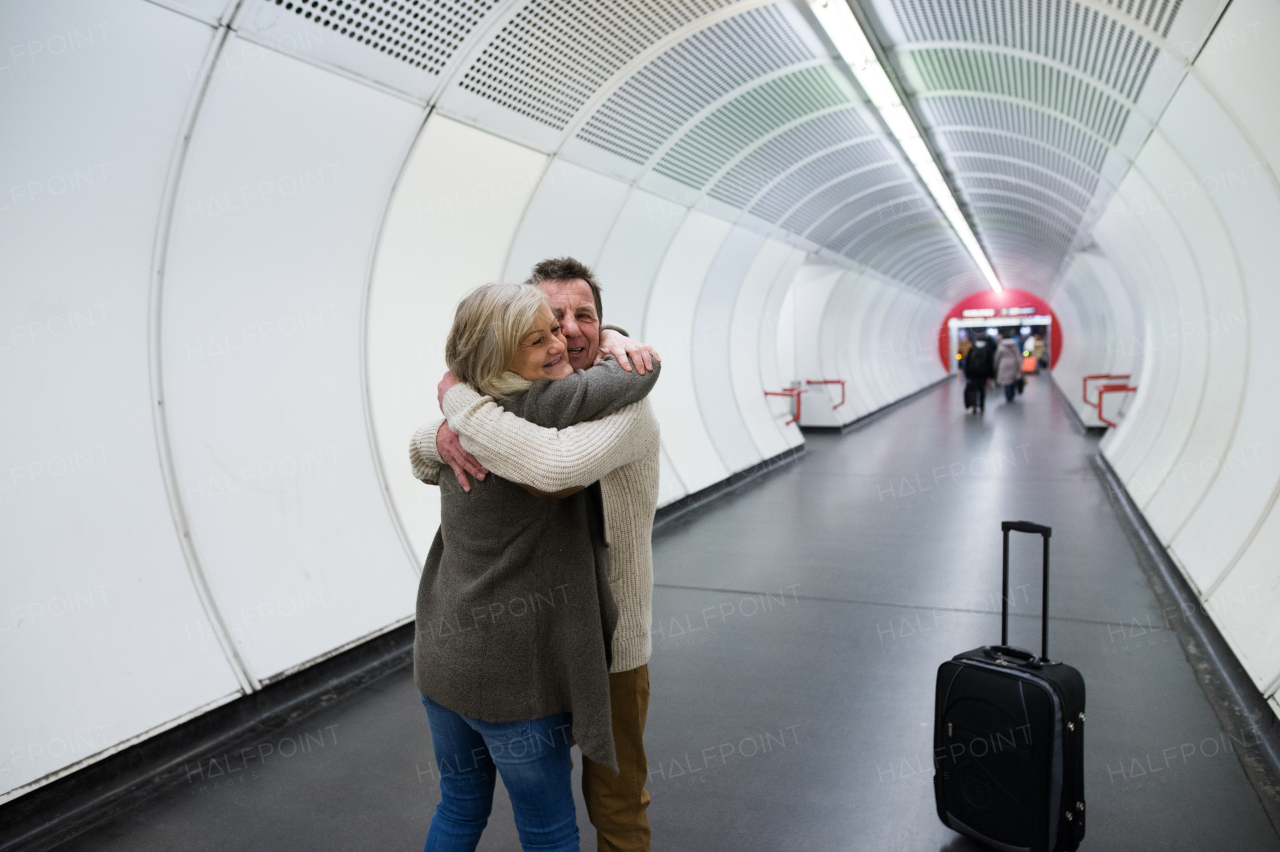 Beautiful senior couple in winter clothes in the hallway of subway in Vienna hugging. Man welcoming his wife.