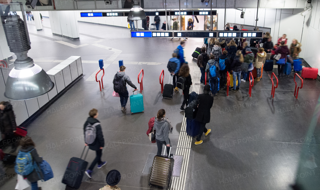 Travellers walk through train station carrying suitcases, Vienna, Austria.