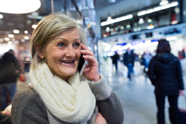 Beautiful senior woman in the hallway of subway in Vienna, holding a smart phone, making phone call.