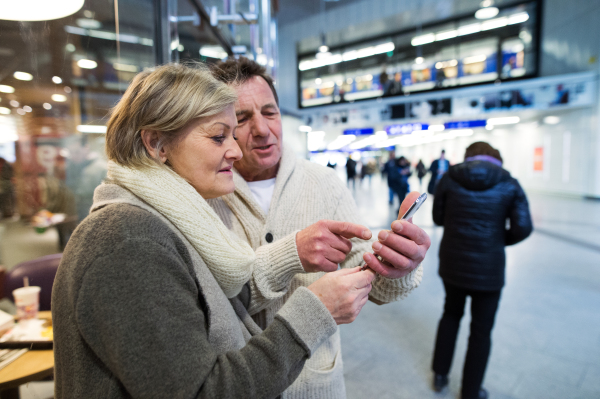 Beautiful senior couple in the hallway of subway in Vienna, holding a smart phone.