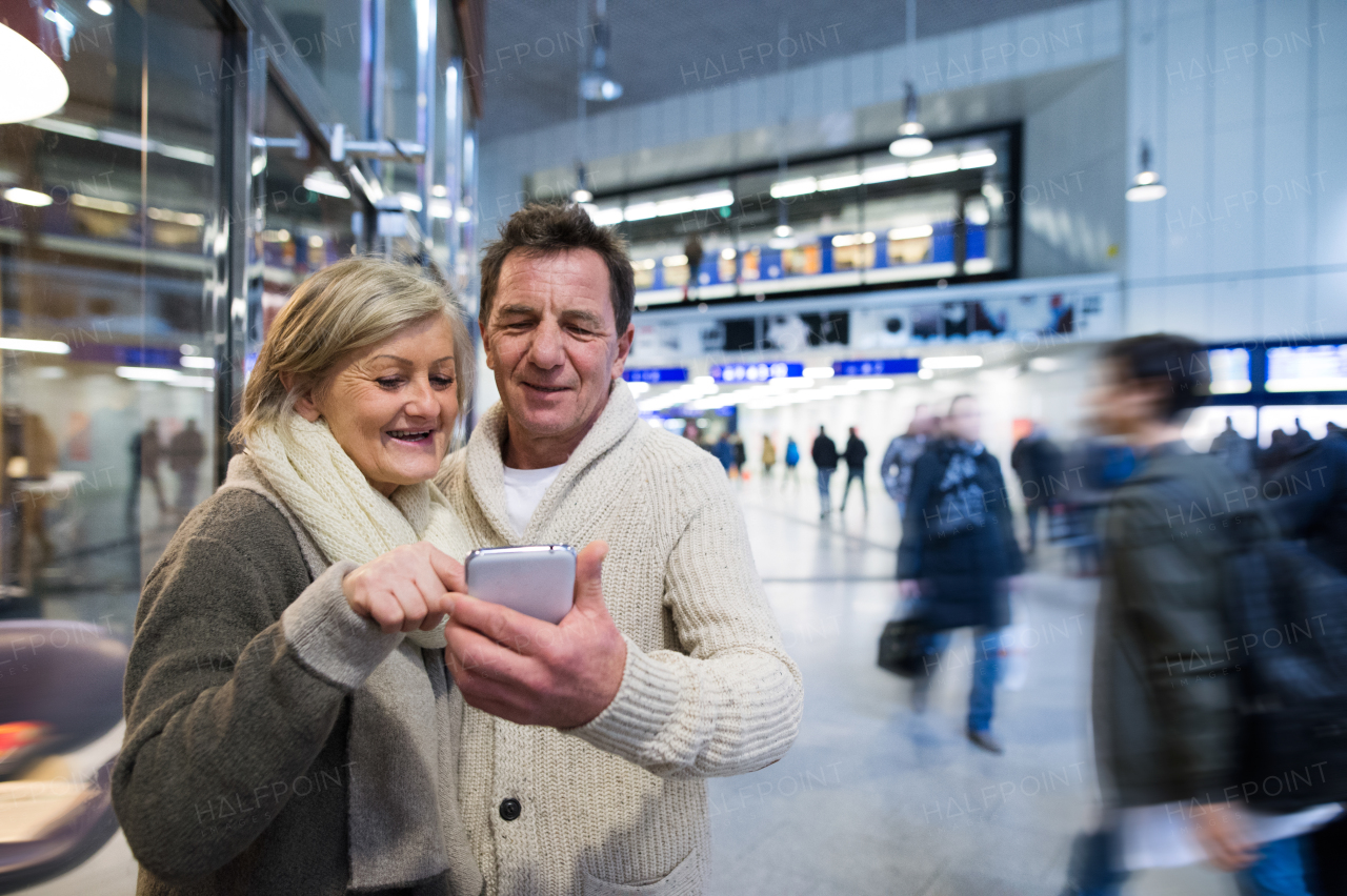 Beautiful senior couple in the hallway of subway in Vienna, holding a smart phone.