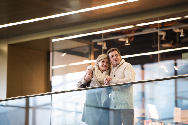 Beautiful senior couple waiting at the train station in Vienna, Austria, hugging.