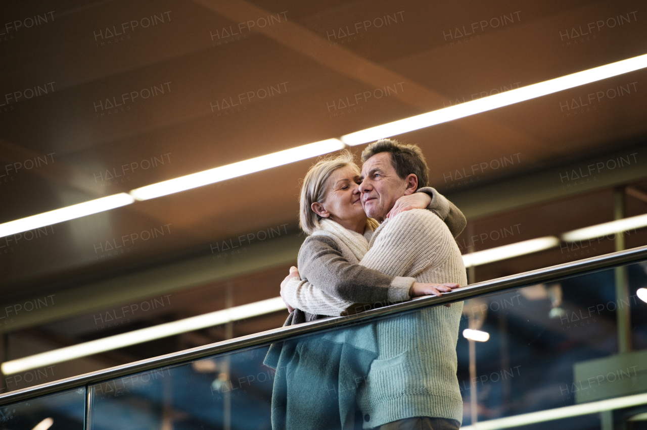 Beautiful senior couple waiting at the train station in Vienna, Austria, kissing.