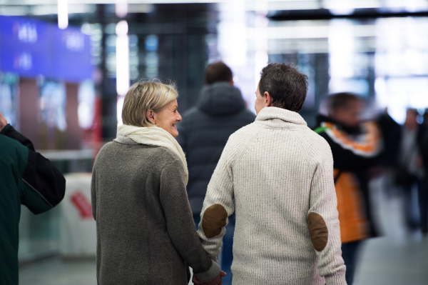 Beautiful senior couple walking in the hallway of subway in Vienna, holding hands. Rear view.