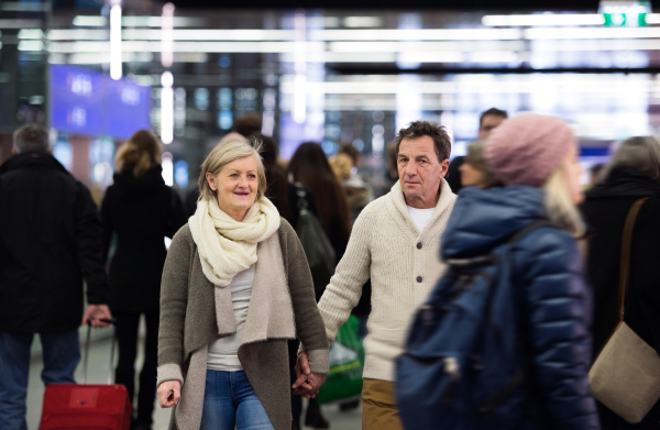 Beautiful senior couple walking in the crowded hallway of subway in Vienna, holding hands.