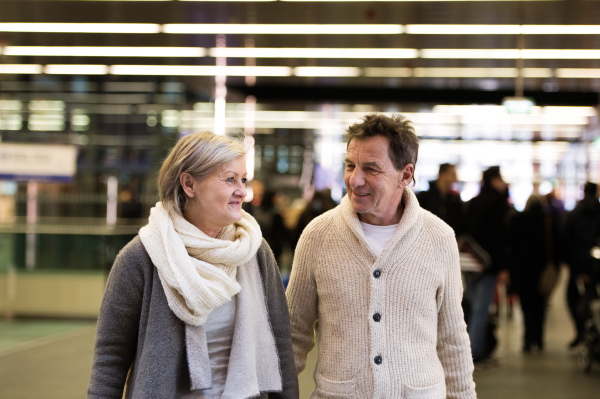 Beautiful senior couple walking in the crowded hallway of subway in Vienna, holding hands.