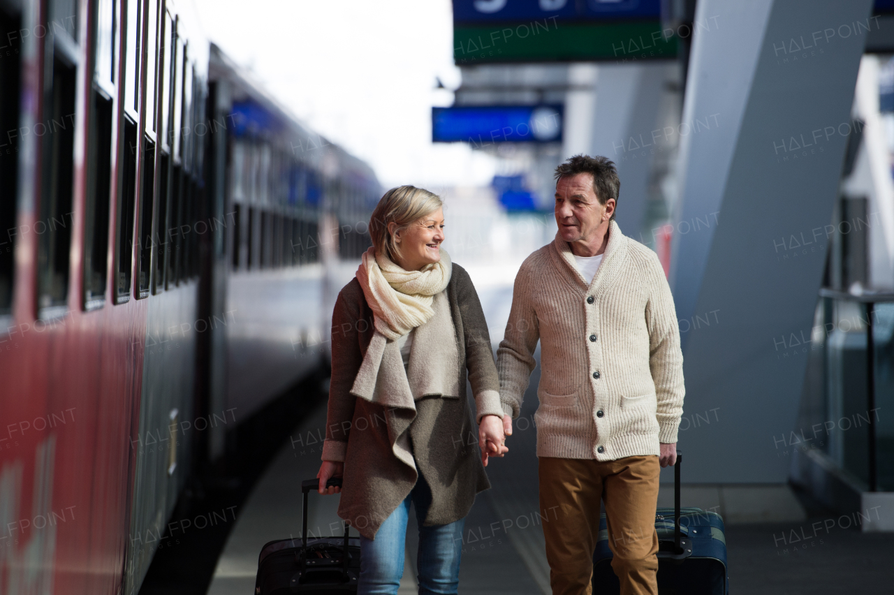 Beautiful senior couple on trainstation pulling a trolley luggage.