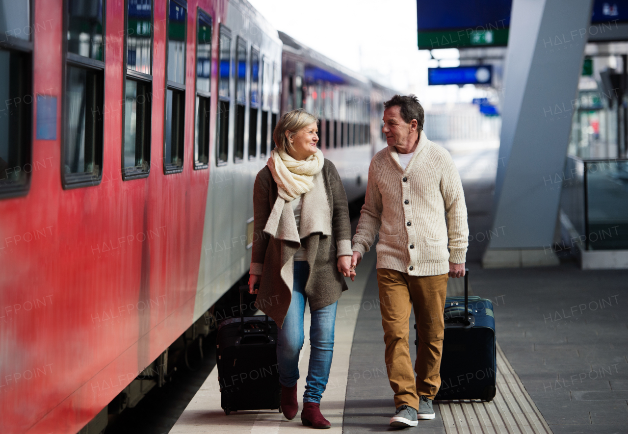 Beautiful senior couple on trainstation pulling a trolley luggage.