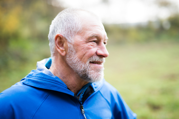 Close up of senior runner in nature. Man in blue sweatshirt, resting, smiling.