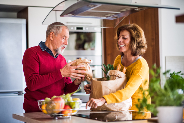 Senior couple preparing food in the kitchen. An old man and woman inside the house.