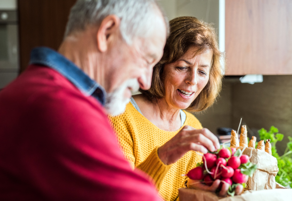 Senior couple preparing food in the kitchen. An old man and woman inside the house.