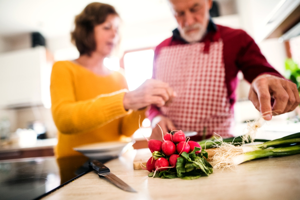 Senior couple preparing food in the kitchen. An old man and woman inside the house.