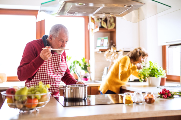 Senior couple preparing food in the kitchen. An old man and woman inside the house.