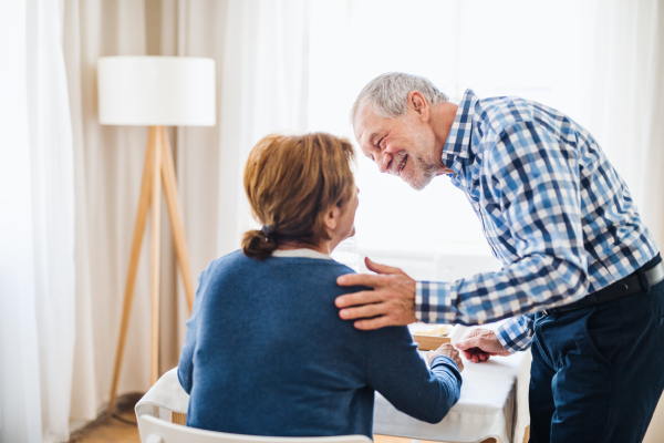 A happy senior couple sitting at the table at home, having breakfast.