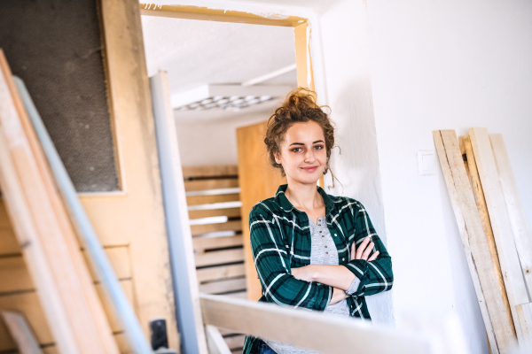 Small business of a young woman. Beautiful young woman worker in a workroom, crossed arms.