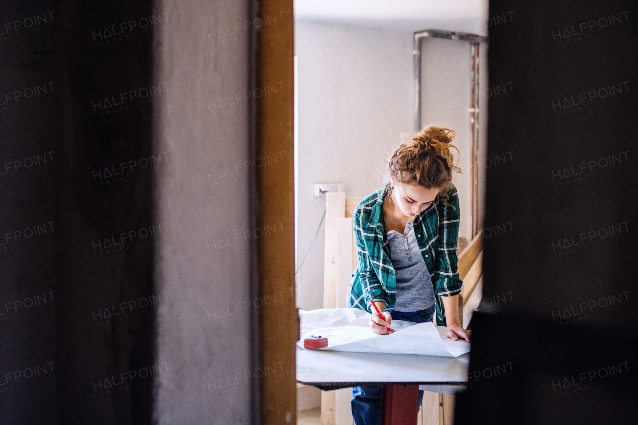 Small business of a young woman. Beautiful young woman worker in a workroom. Female carpenter sketching a project.