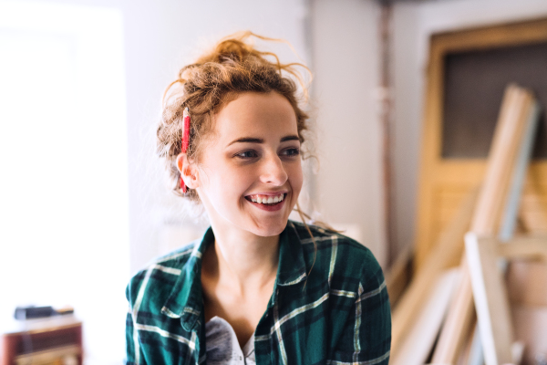 Small business of a young woman. Beautiful young woman worker in a workroom, pencil behind ear.