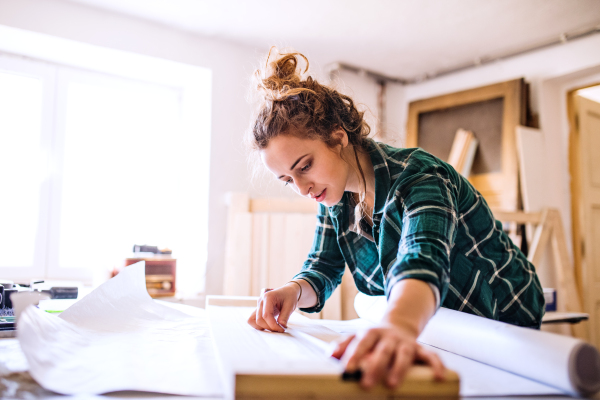 Small business of a young woman. Beautiful young woman worker in a workroom, measuring wood.