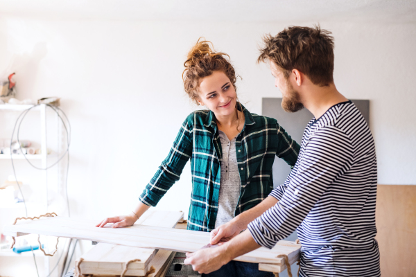 Small business of a young couple. Man and woman worker in the carpenter workroom.