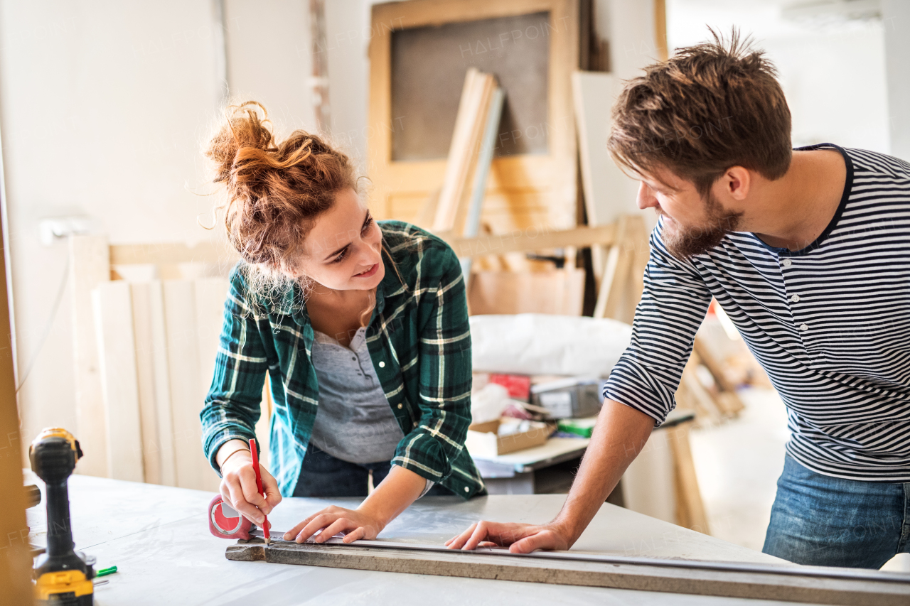 Small business of a young couple. Man and woman worker in the carpenter workroom.