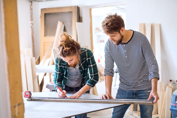 Small business of a young couple. Man and woman worker in the carpenter workroom.