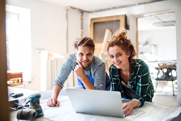 Man and woman worker with laptop in the carpenter workroom. Young couple working together.