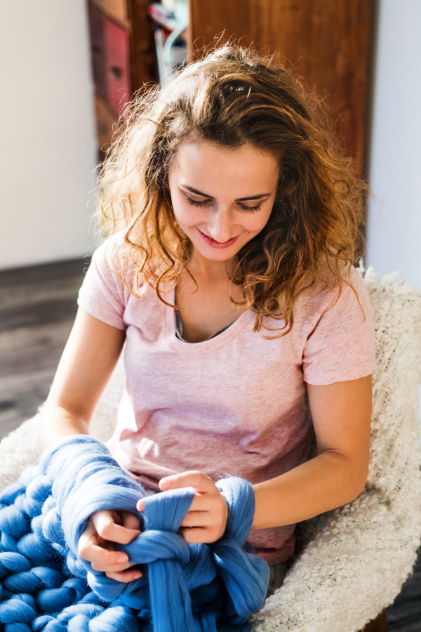 Small business of a young woman. Young woman hand-knitting a wollen blanket.