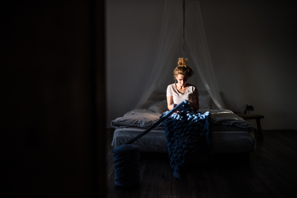 Small business of a young woman. Young woman hand-knitting a wollen blanket.