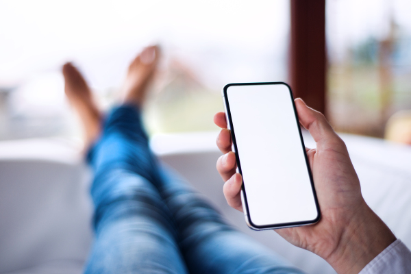 A mockup image of a man holding smartphone with blank white screen. Smart home control system.