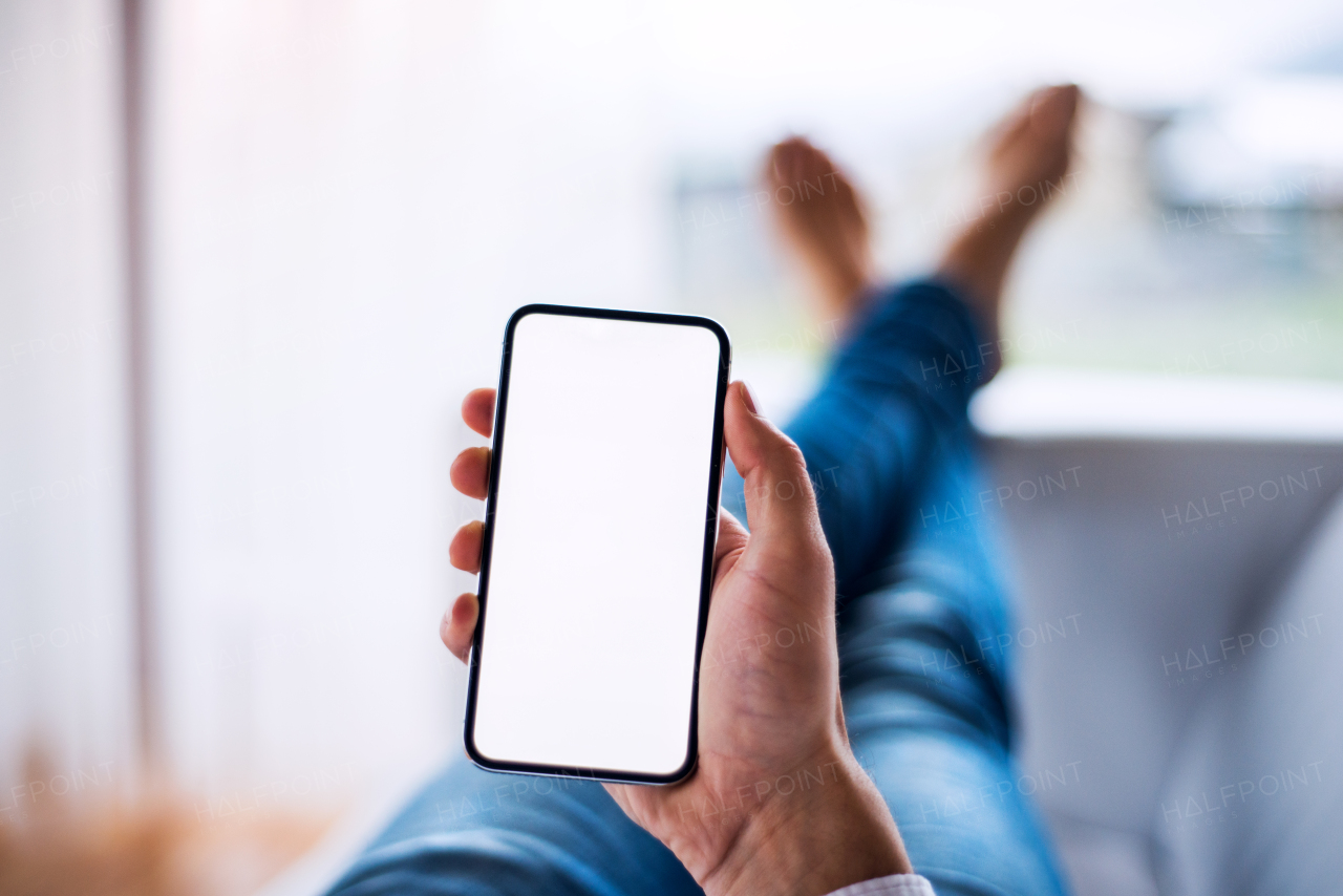 A mockup image of a man holding smartphone with blank white screen. Smart home control system.