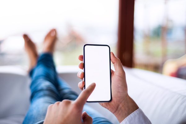 A mockup image of a man holding smartphone with blank white screen. Smart home control system.