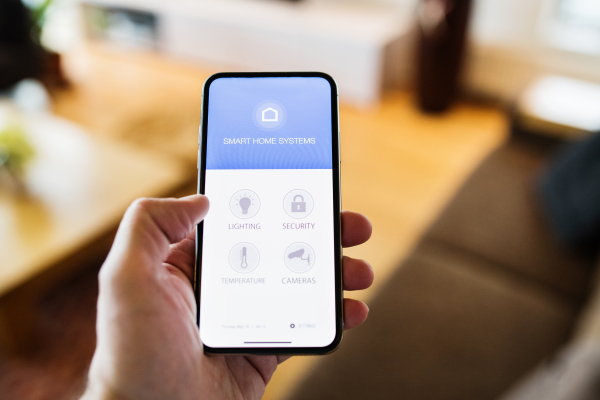 An unrecognizable woman holding a smartphone with smart home control system.