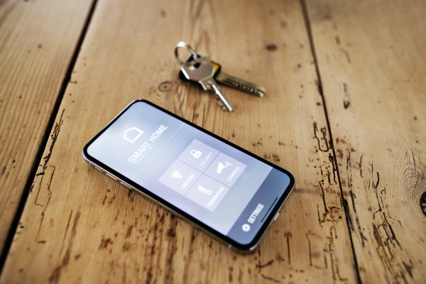 A smartphone with smart home control system. Keys on the old wooden table. Top view.