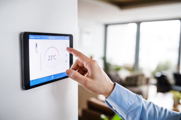 An unrecognizable man pointing to a tablet with smart home control system.