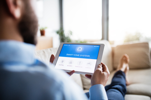 An unrecognizable man holding a tablet with smart home control system.