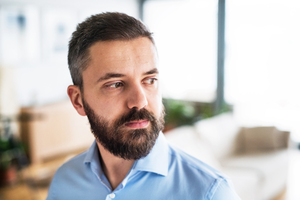 A portrait of a handsome man standing at home.