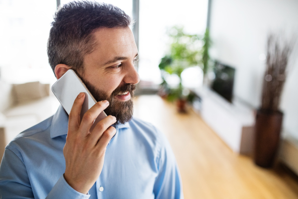 A handsome man with a smartphone making a phone call at home.