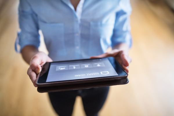 An unrecognizable woman holding a tablet with smart home control system.