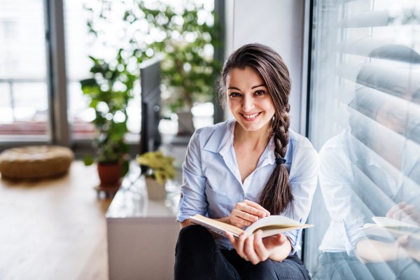 A woman sitting by the window, reading a book. Smart home control system.