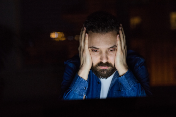 A handsome man working on a laptop at home at night.