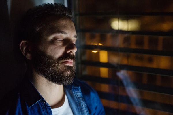 A handsome man slepping by the window at home at night. Close up.