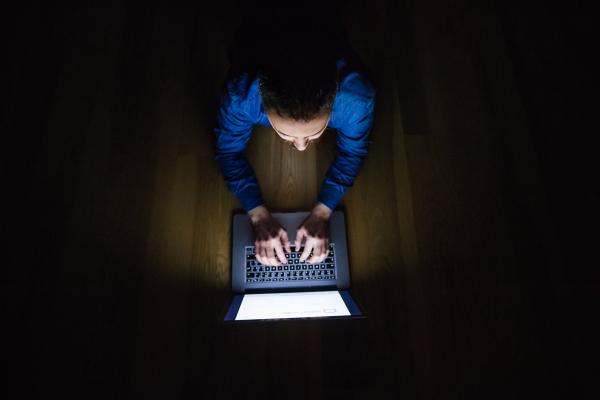 A man working on a laptop at home at night. Smart home control system. Top view.