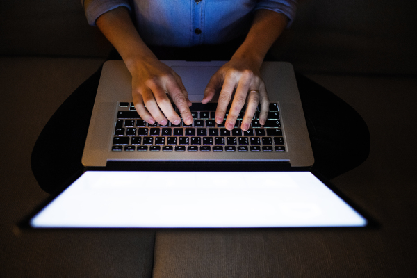 An unrecognizable woman working on a laptop. Top view.