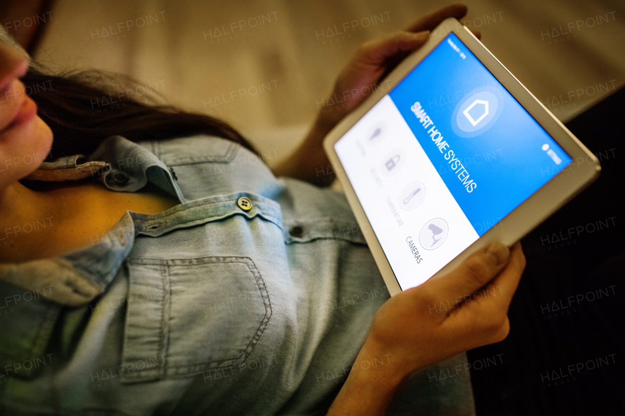 An unrecognizable woman holding a tablet with smart home control system.