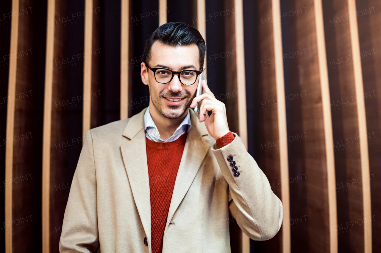 Young handsome man with smartphone standing against wooden wall, making a phone call.