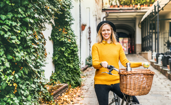 Young beautiful woman with bicycle standing in sunny spring town.