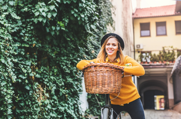 Young beautiful woman with bicycle standing in sunny spring town.