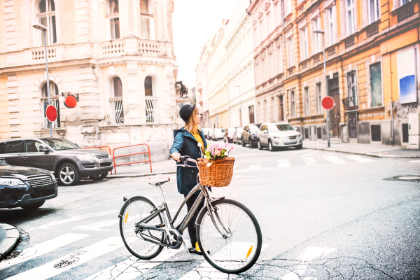 Young beautiful woman with bicycle in sunny spring town.