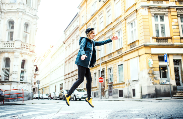 Young woman with yellow boots walking on the street in town, jumping.